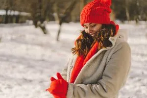 Mulher na neve vestida com casacos e toca devido ao frio