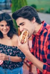 Homem comendo cachorro quente