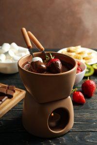 Imagem de fondue de chocolate, com frutas e marshmallow