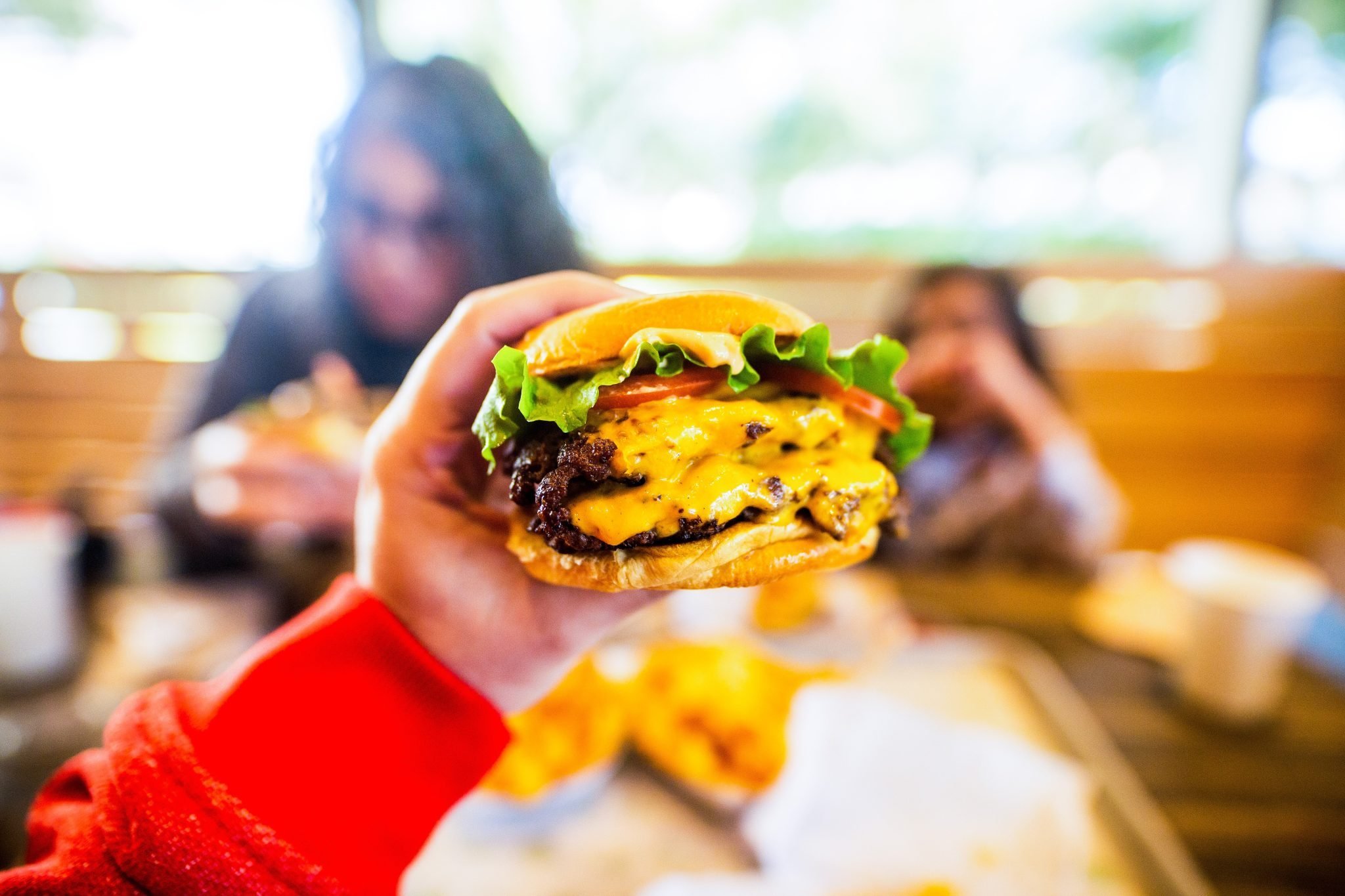 mulher sguando um hamburguer fast food na mão